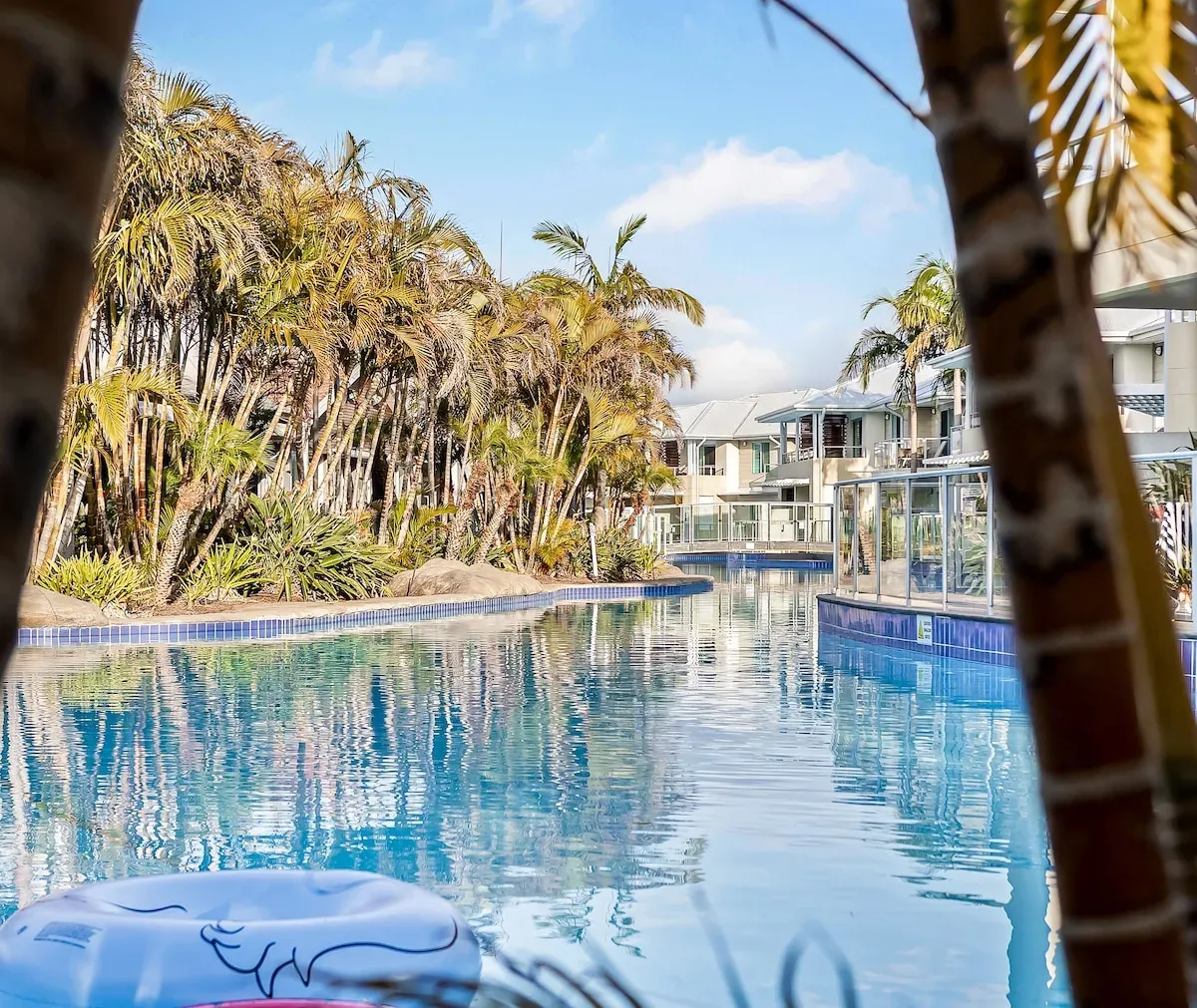 Resort pool framed by palms and balconies at Oaks Pacific Blue