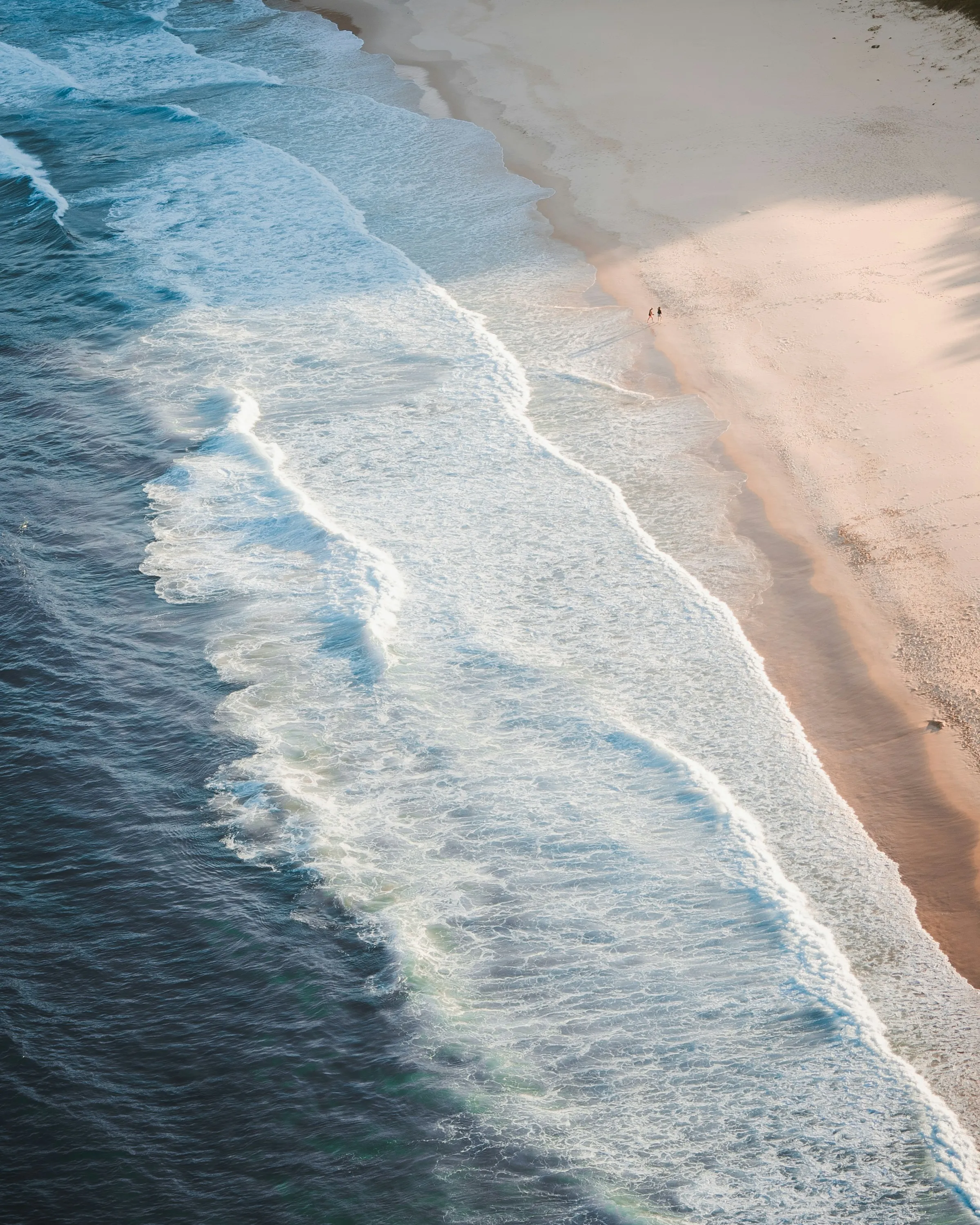 Waves rolling onto a long Port Stephens beach, seen from above